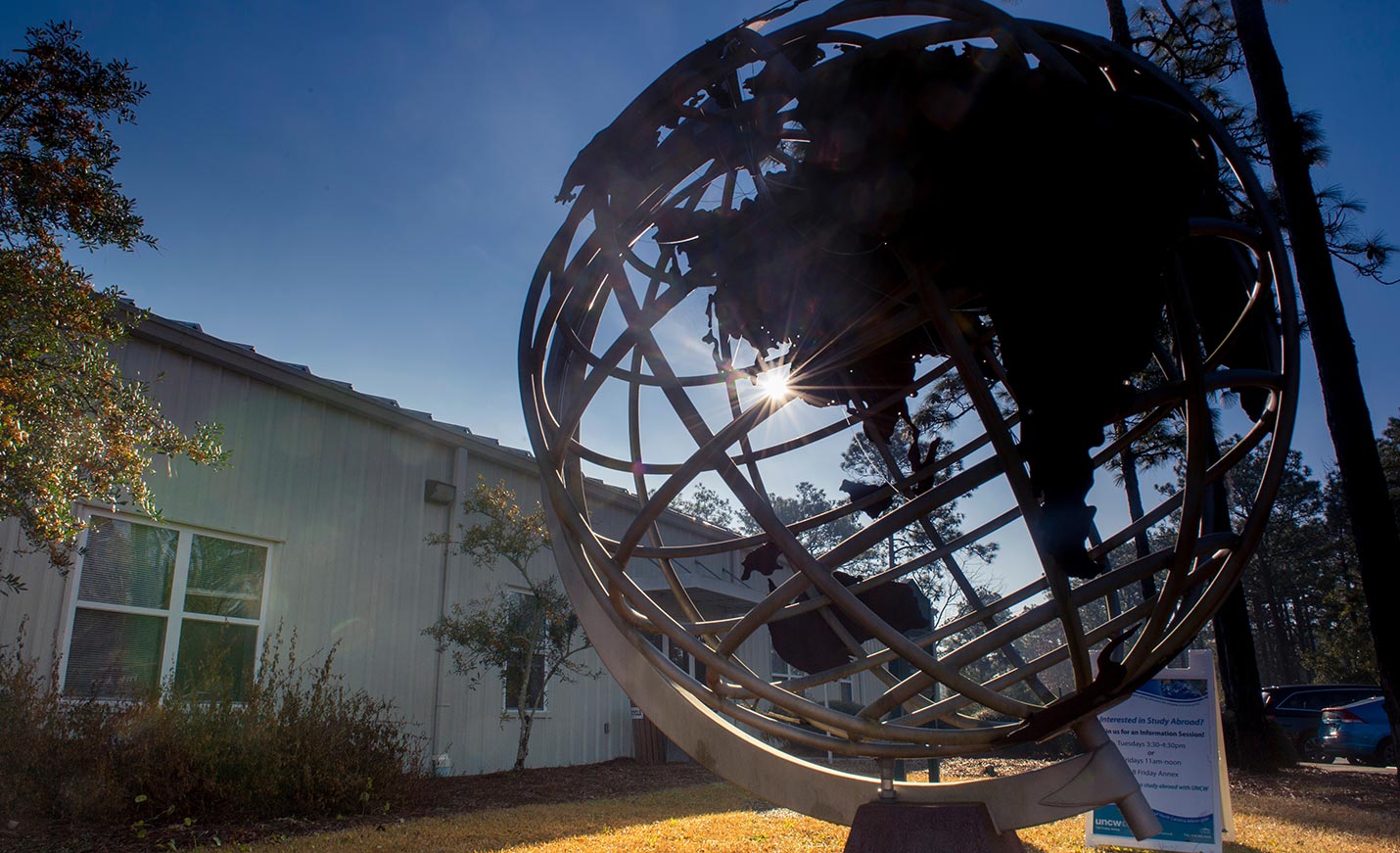 The metal globe outside International Programs with sun shining through it