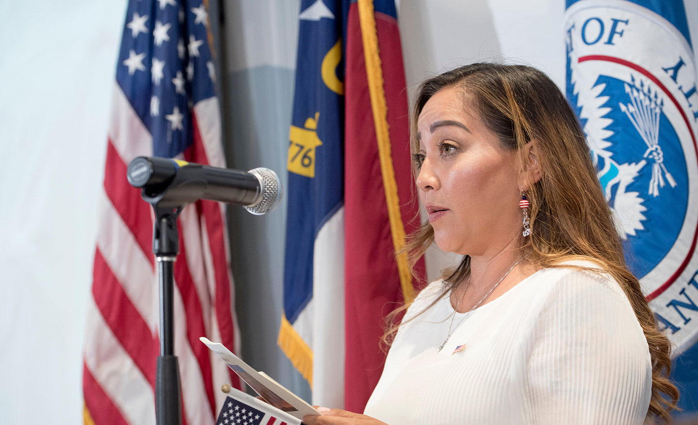 A woman speaks with flags in the background