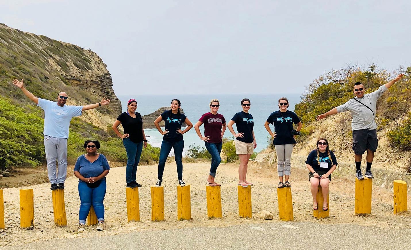A group of people stand on pylons on a beach 