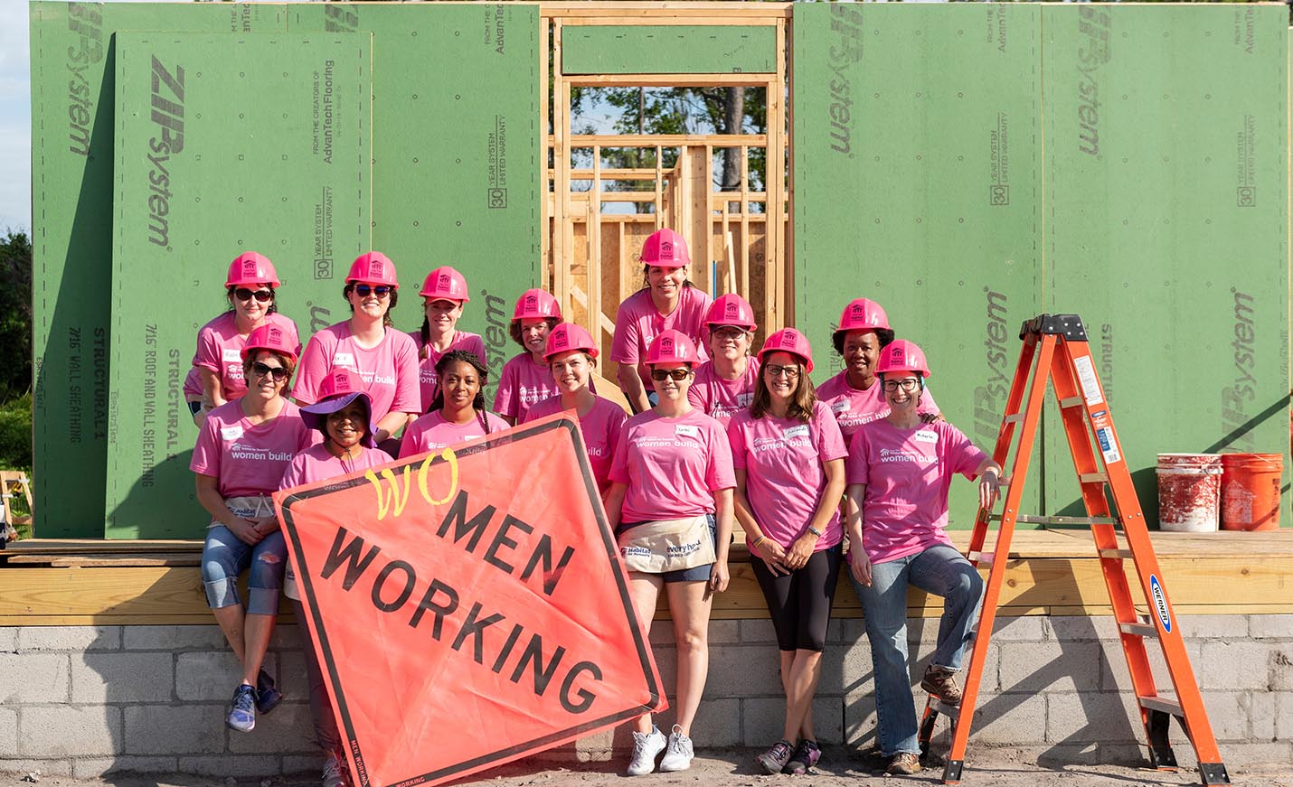 Femaie students in pink shirts at a construction project with a women working sign