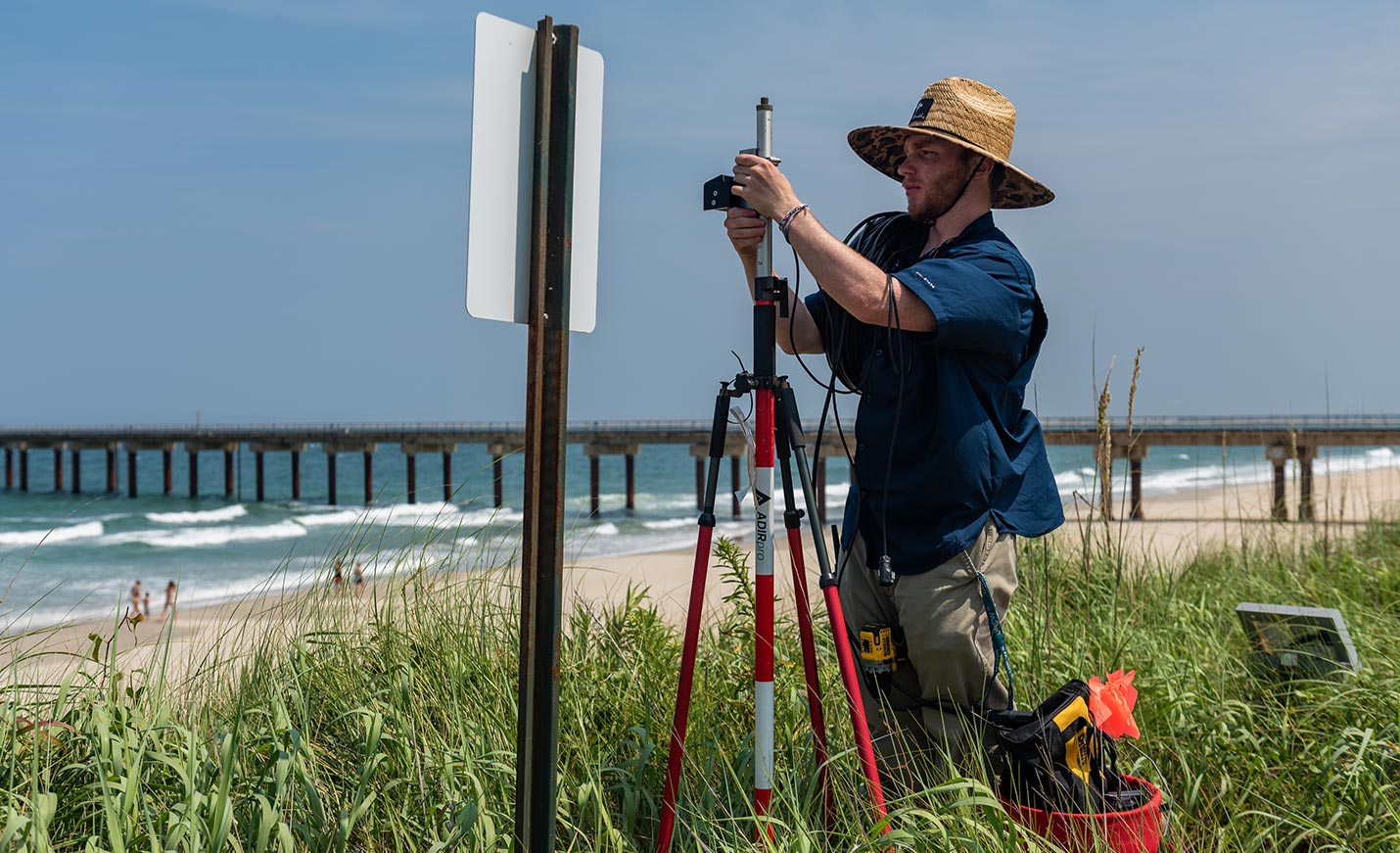 student installing LiDAR technology used to measure waves and coastal change during storm impact