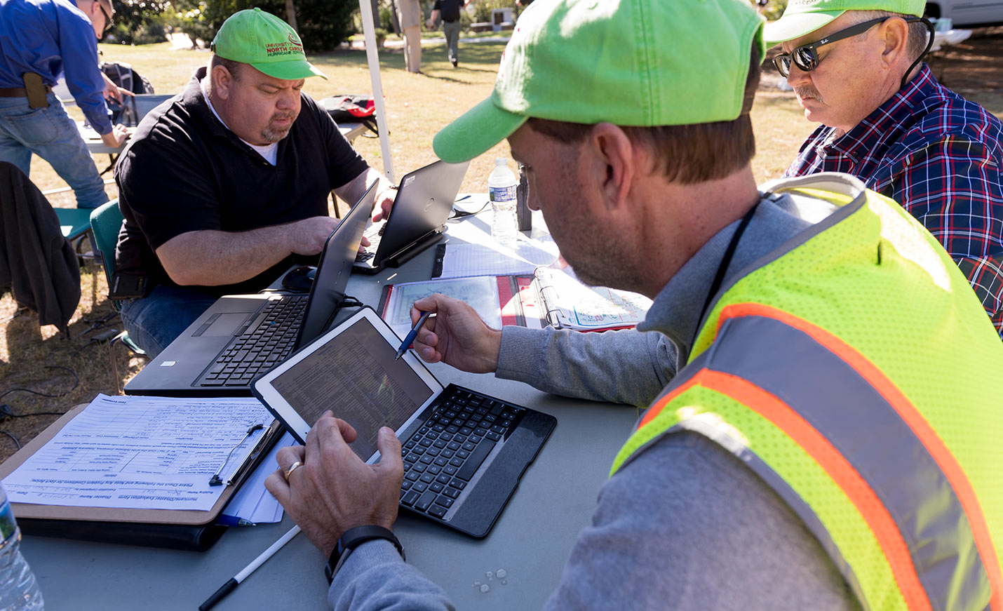 people work outdoors on laptops during a disaster drill