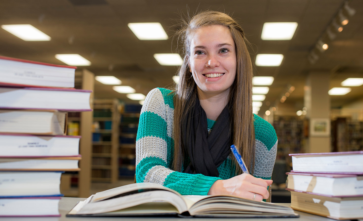 Smiling student with book in library