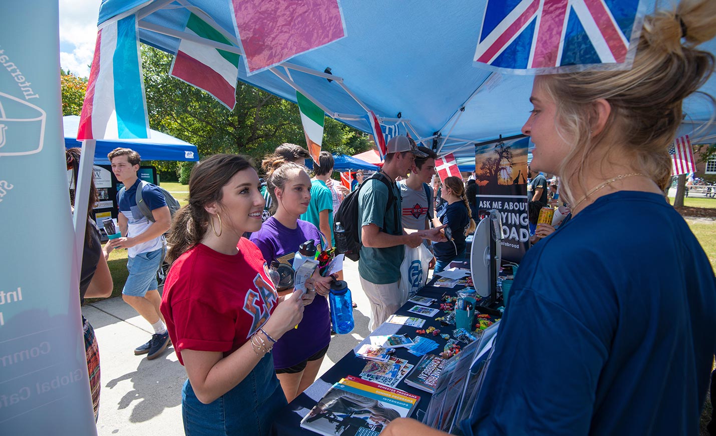students talking at an Involvement Carnival booth for UNCW Study Abroad