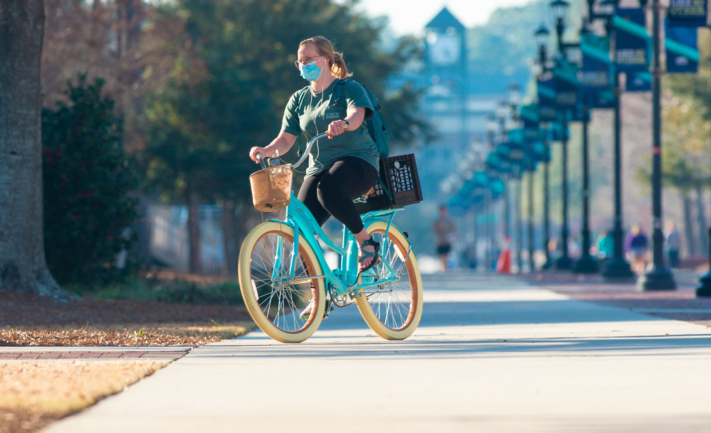 student riding teal bicycle on chancellor's walk