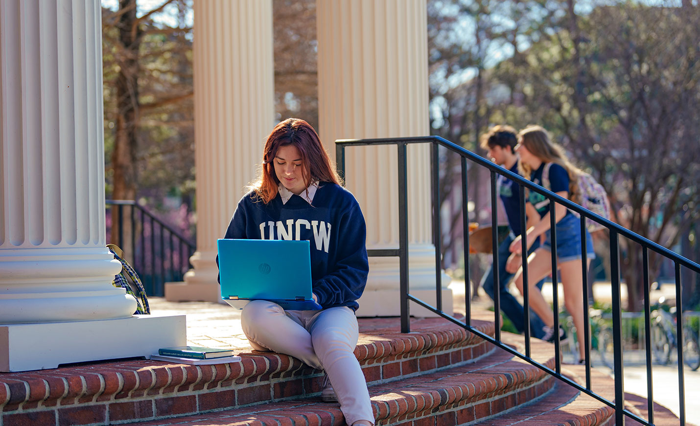 student working on a laptop outdoors on the stairs of Randall Library