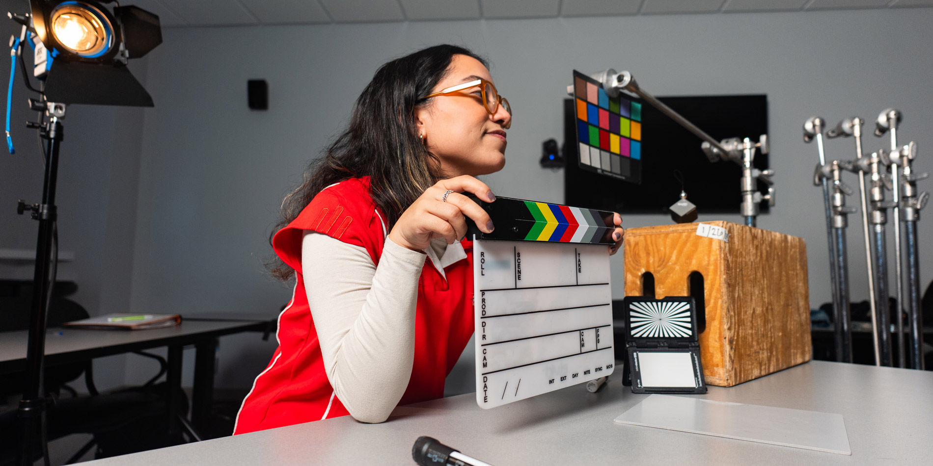 Student learning about color and lighting in film, holding a clapper board.