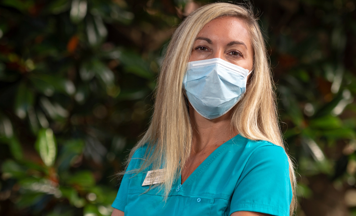 Close-up of a women in scrubs wearing a paper mask
