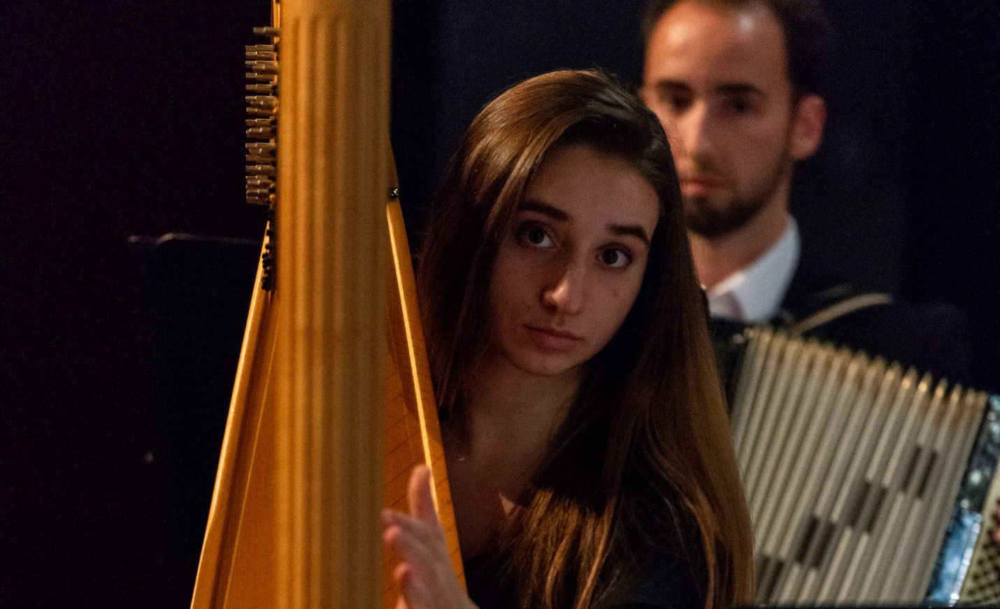 A close-up of a female harp player getting ready to perform.