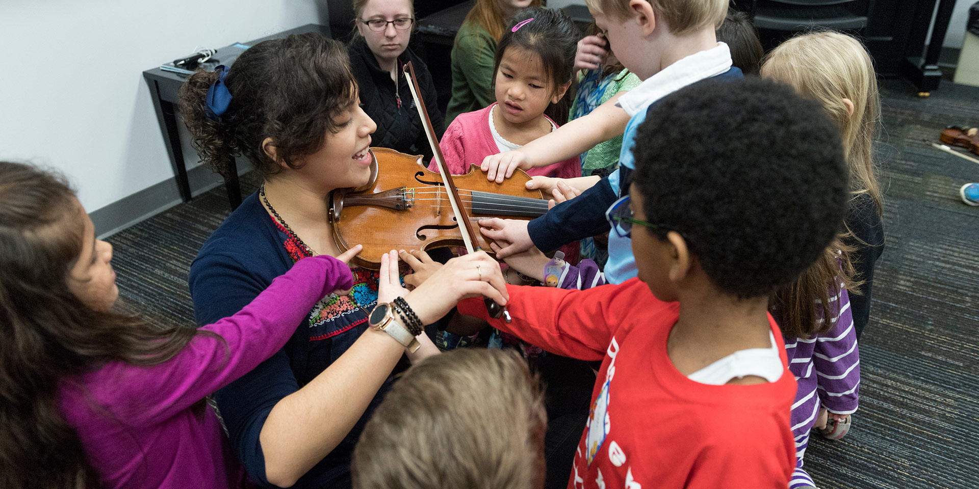 A music teacher plays a violin in a group of children