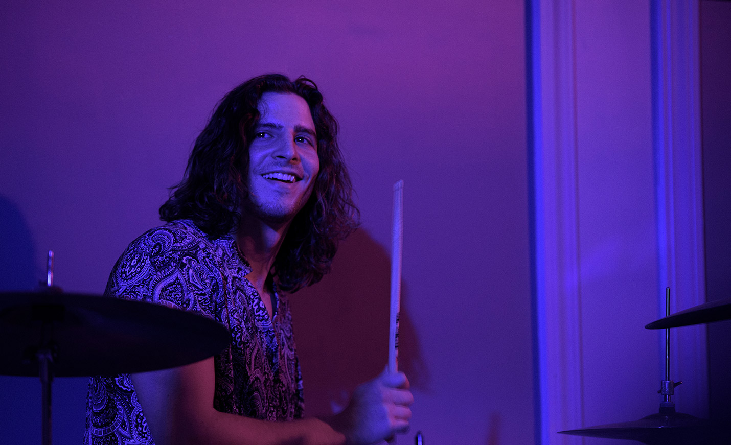 A man holding drumsticks sitting behind a drum set