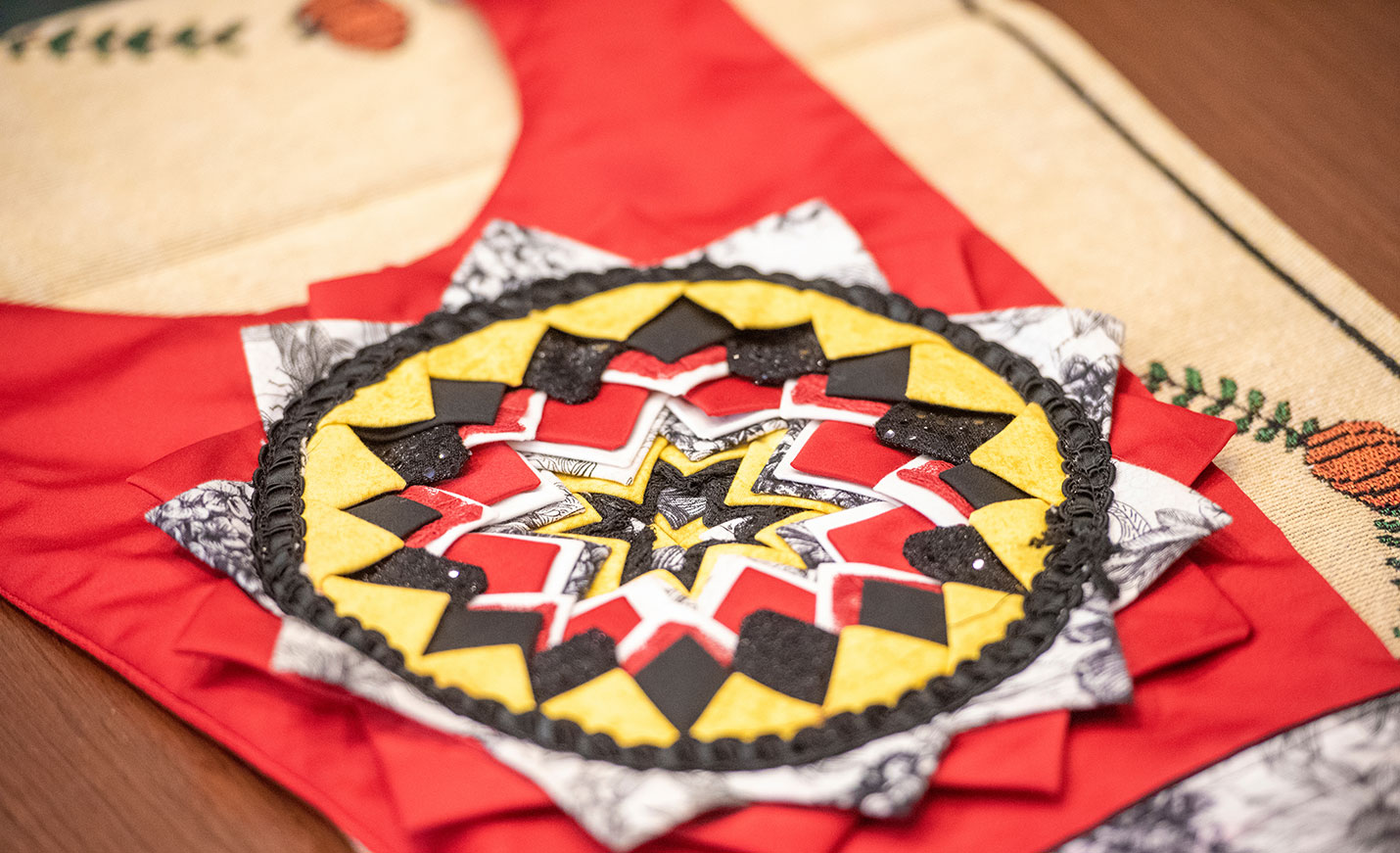A close-up of a Native American textile piece in brilliant red with yellow and black accents