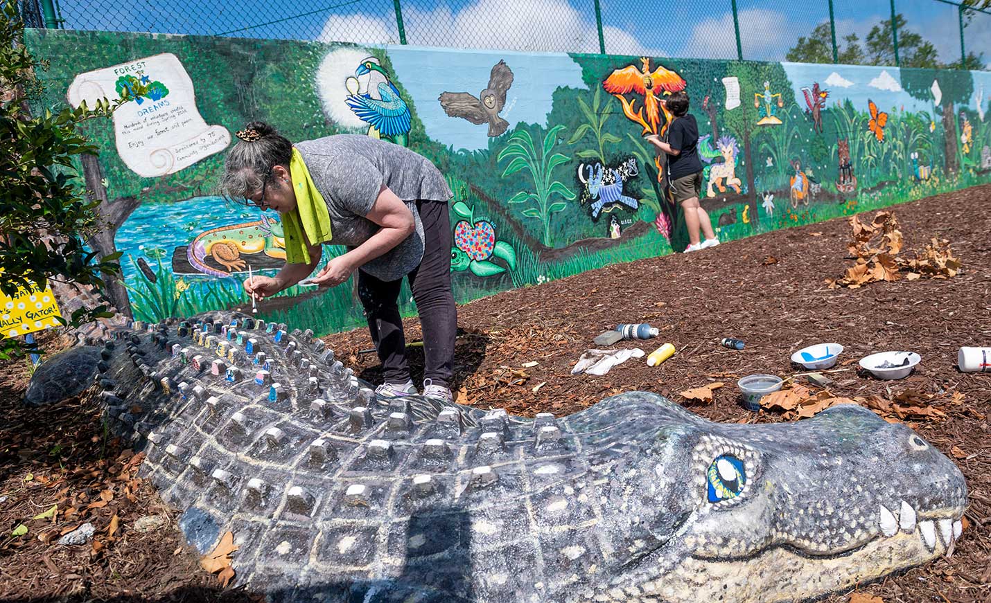 Person painting an alligator sculpture