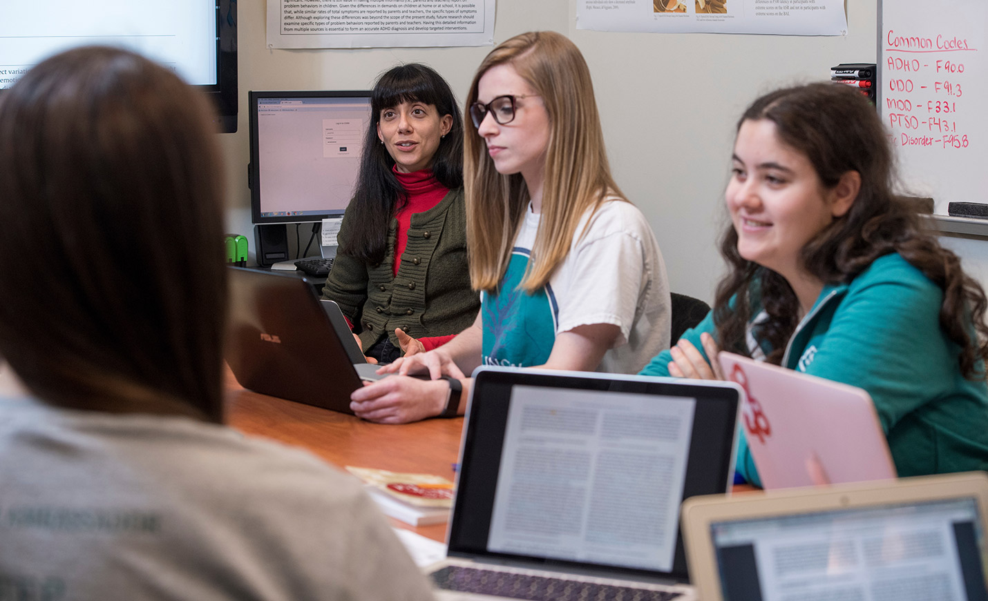 A UNCW faculty member talks with students seated at a table