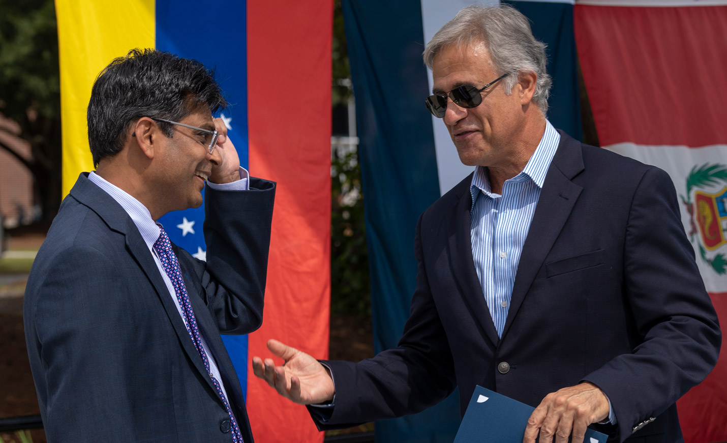 Chancellor Aswani K. Volety and Wilmington Mayor Bill Saffo talk in front of flags representing Latin American nations at the Campus Commons for a Hispanic Heritage Month ceremony.