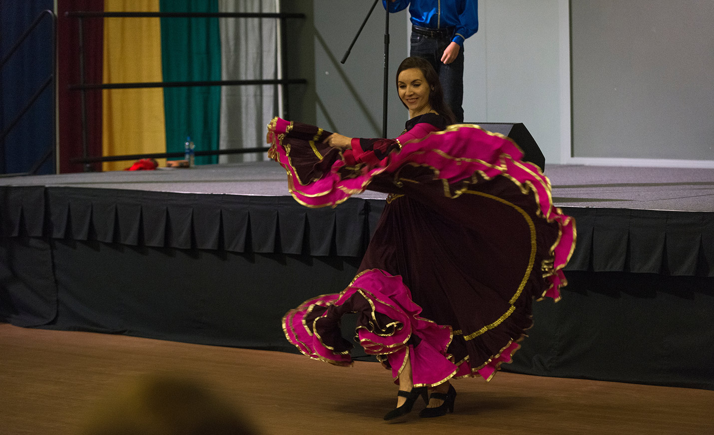A dancer in a colorful black, fuchsia and yellow dress twirls as the dress billows out