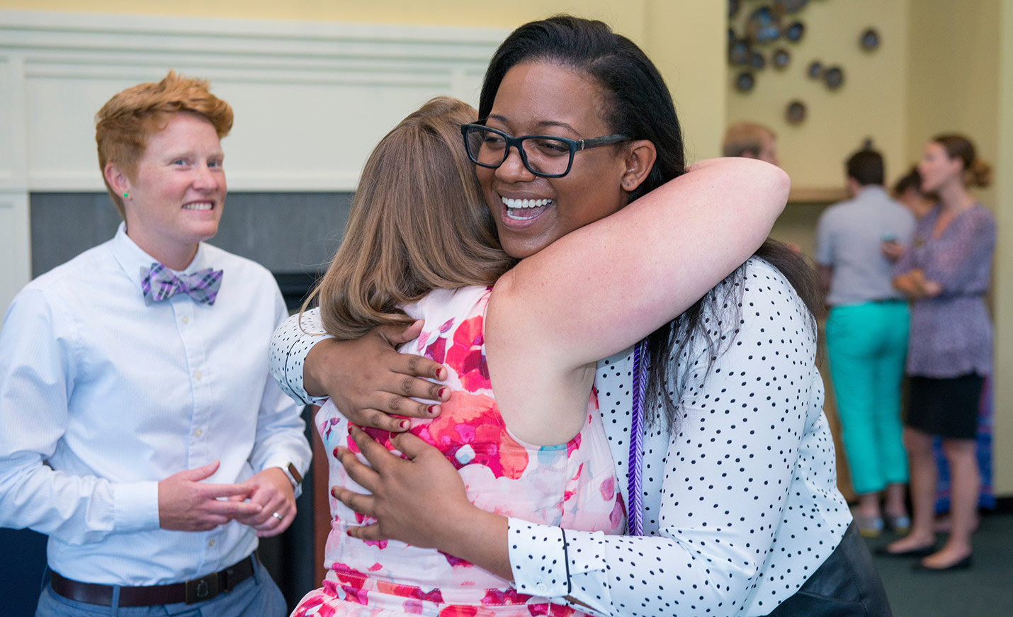 Two women greet each other with a hug and smiles