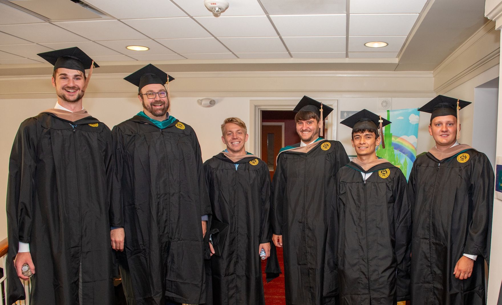 CSB MSAC graduates posing together with caps and gowns. 