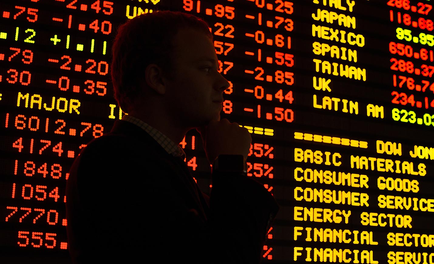 A silhouetted figure in front of the stocks ticker in Congdon Hall