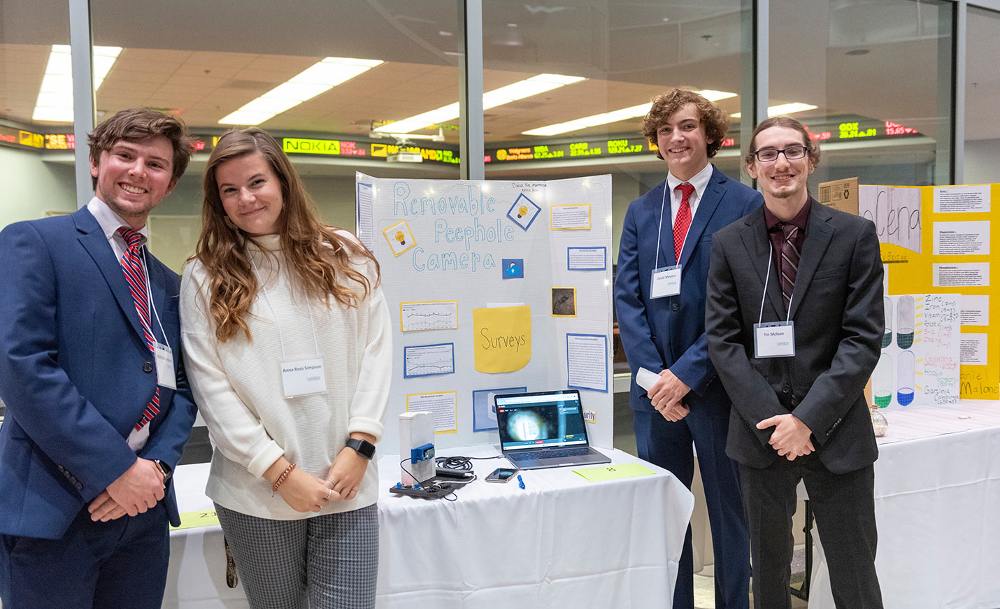 Students in front of a poster proposing an idea for a removable peephole camera