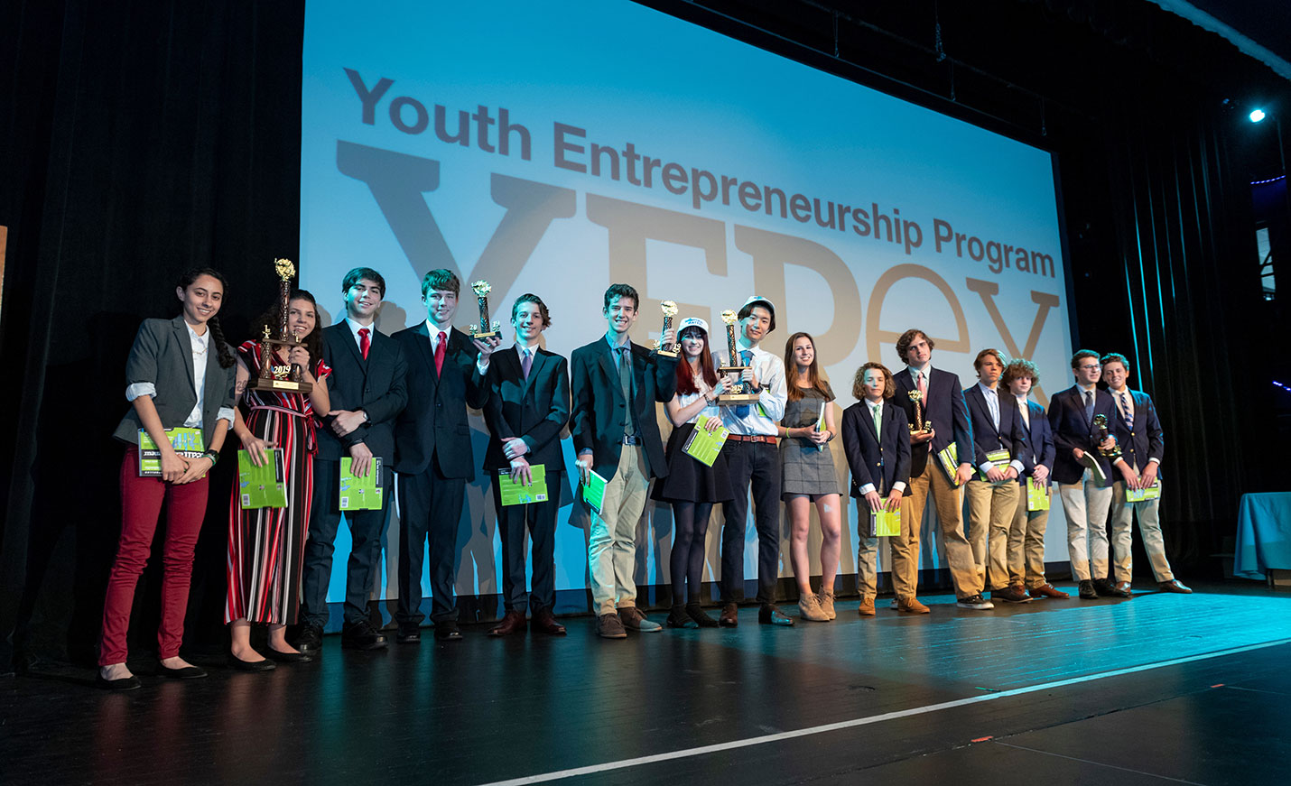A group of high school students onstage at an awards presentation during a Youth Entrepreneurship event