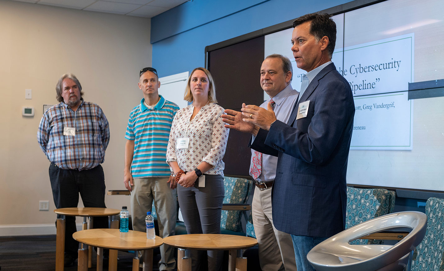 A speaker standing near with other speakers during a cybersecurity conference