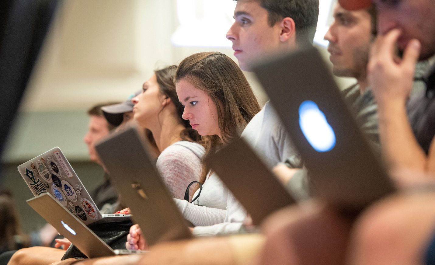 students attend a lecture taking notes on their laptops