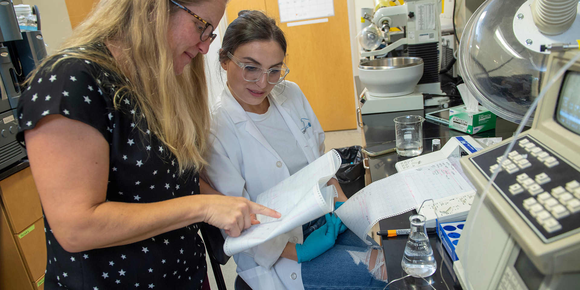 A professor analyzes data with a student in a lab