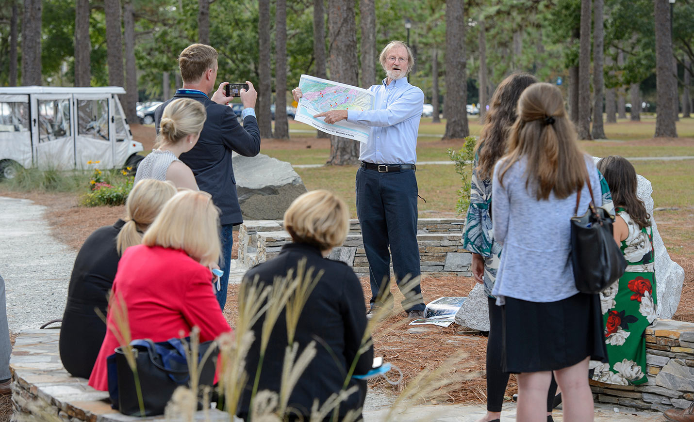 A person points on a map during a tour of a large rock garden