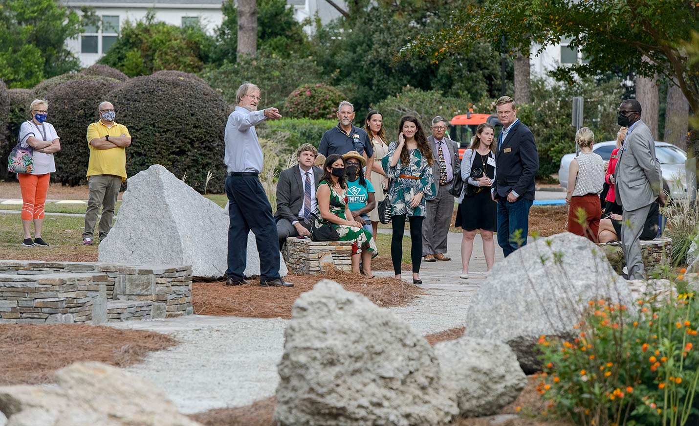A person speaking during a tour of a garden of large rocks