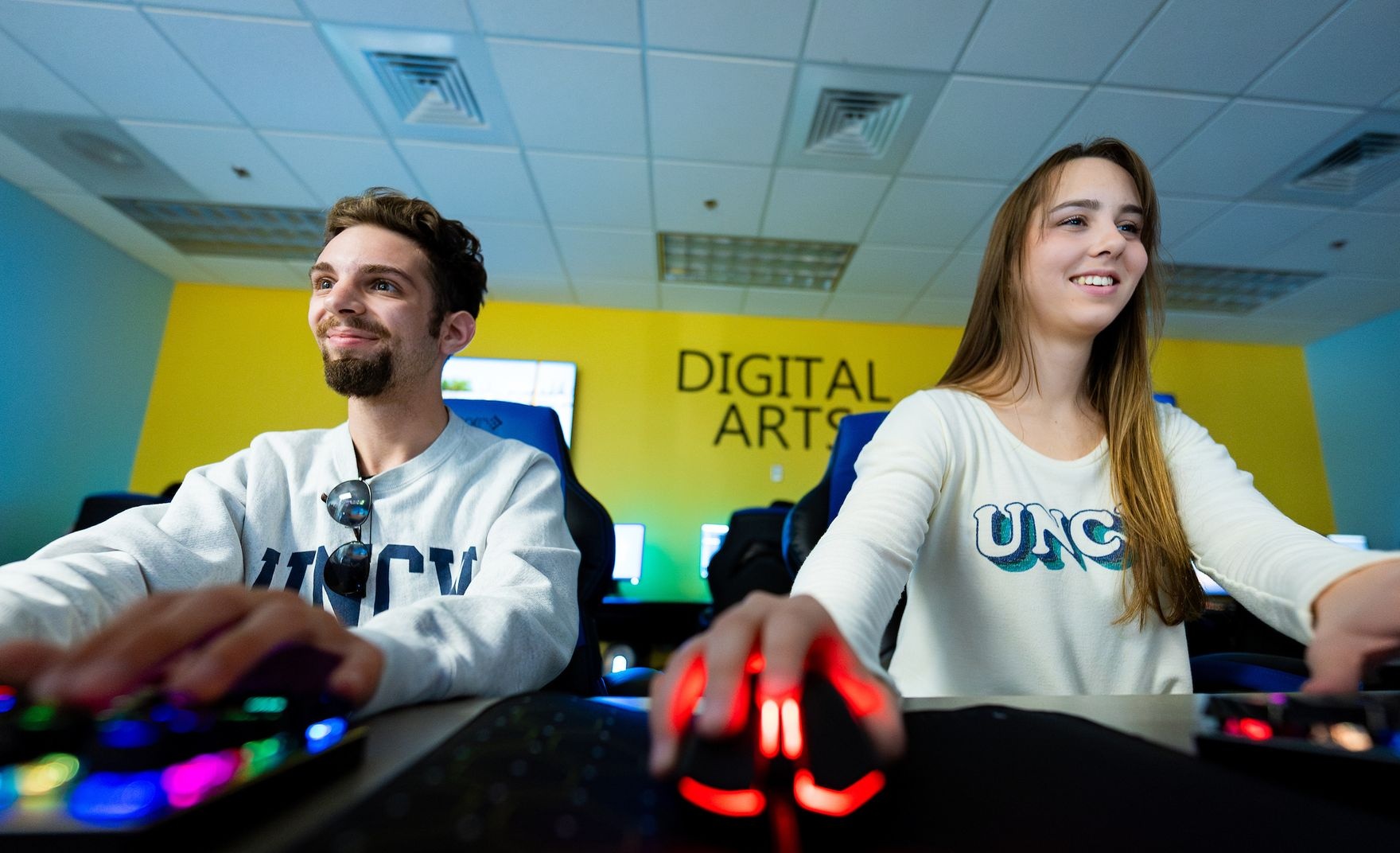two students sitting on computers smiling
