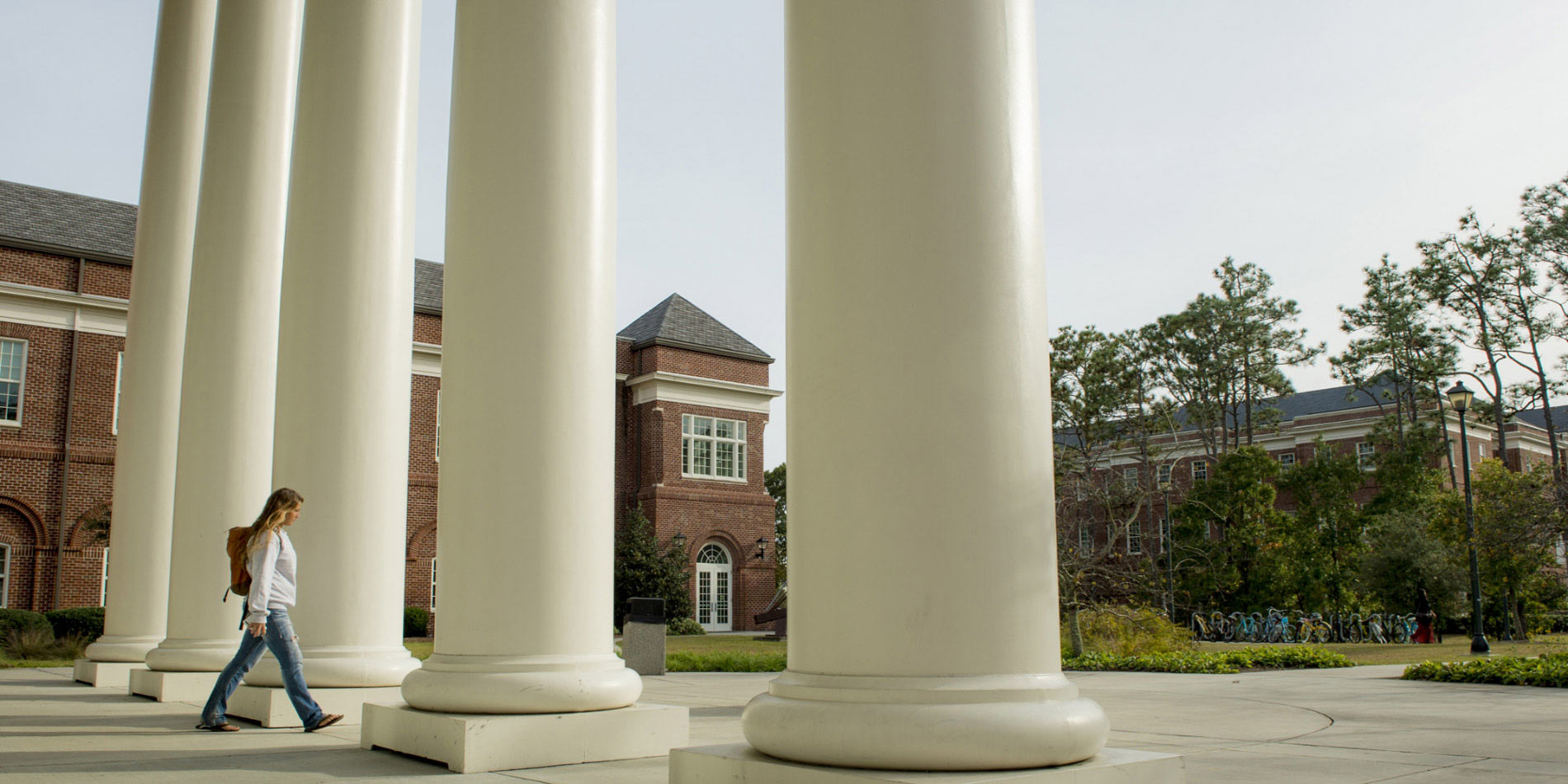Student walking through large columns