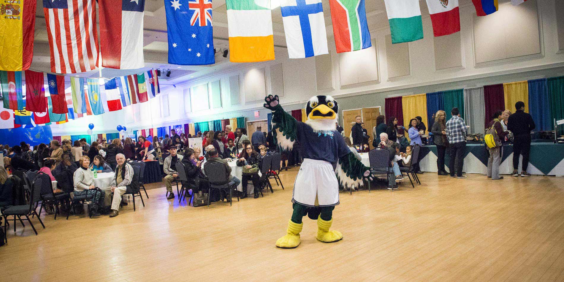 Sammy Seahawk the mascot standing in a crowd waving his hand