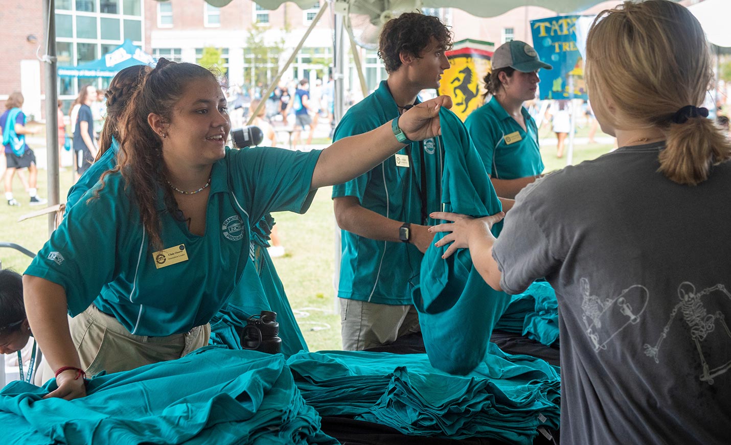 student volunteers pass out free teal shirts to other students
