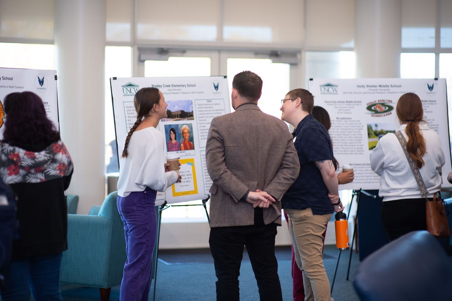 Attendees at the UNCW Spanish Service-Learning Showcase discuss a presentation