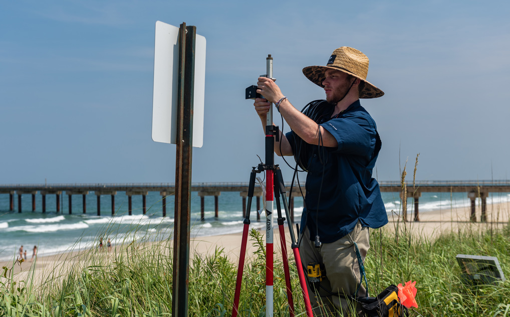 a person works on a lidar installation at the beach.