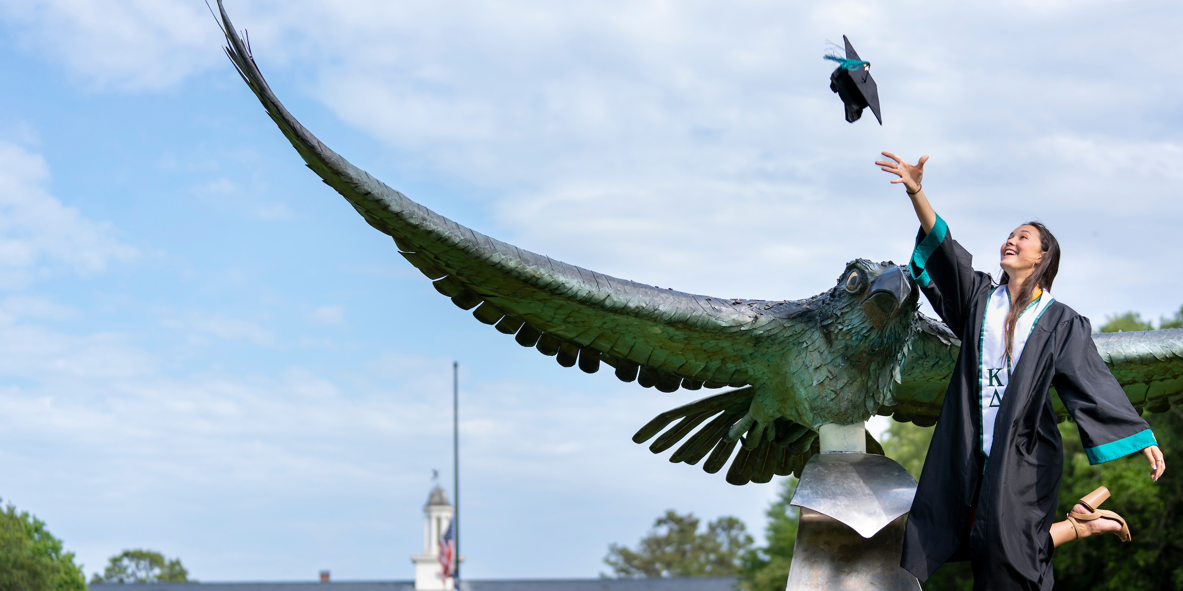 Graduate students tosses cap by the seahawk statue