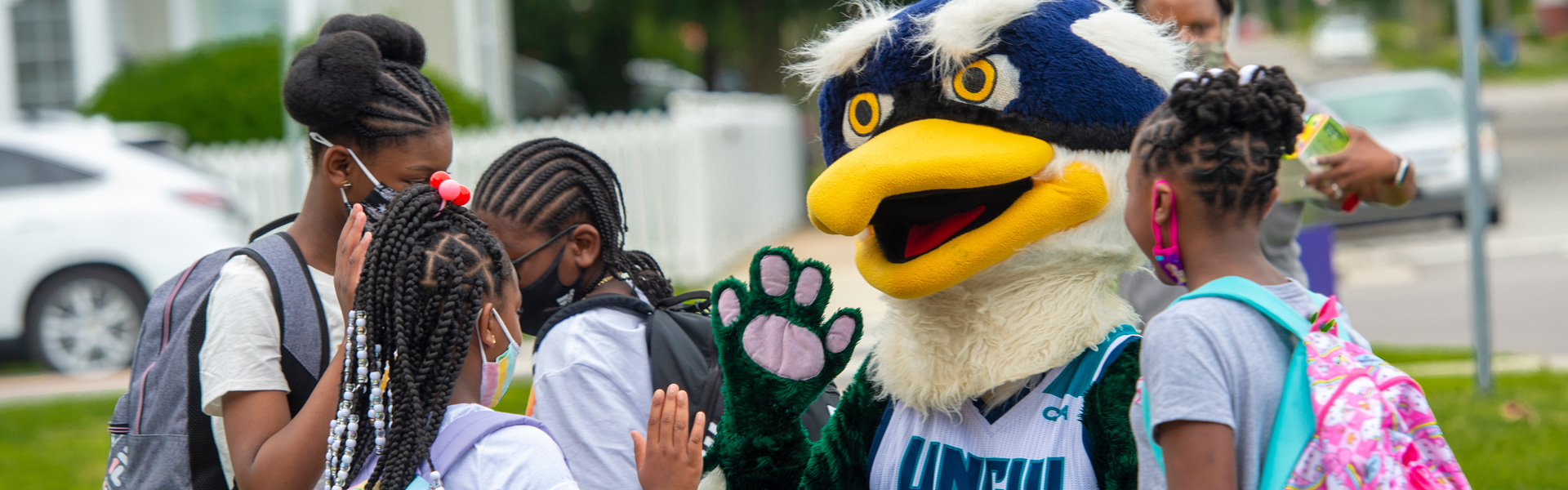 Sammy seahawk high fives some kids on the sidewalk.