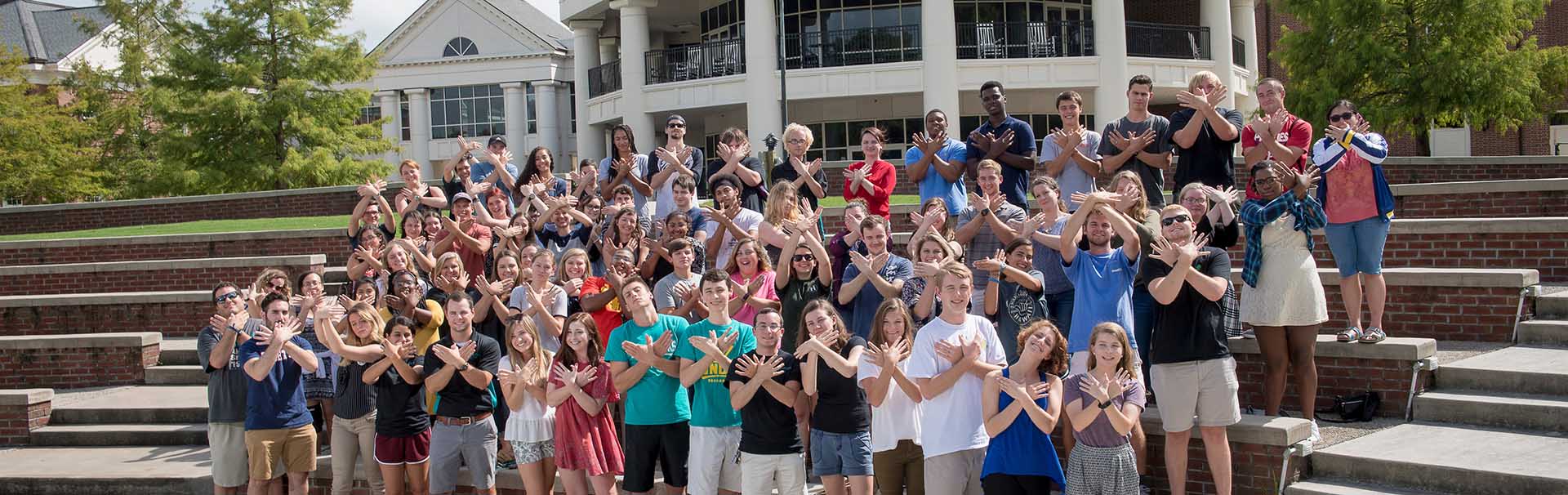 Group of students pose for photo outside of UNCW building