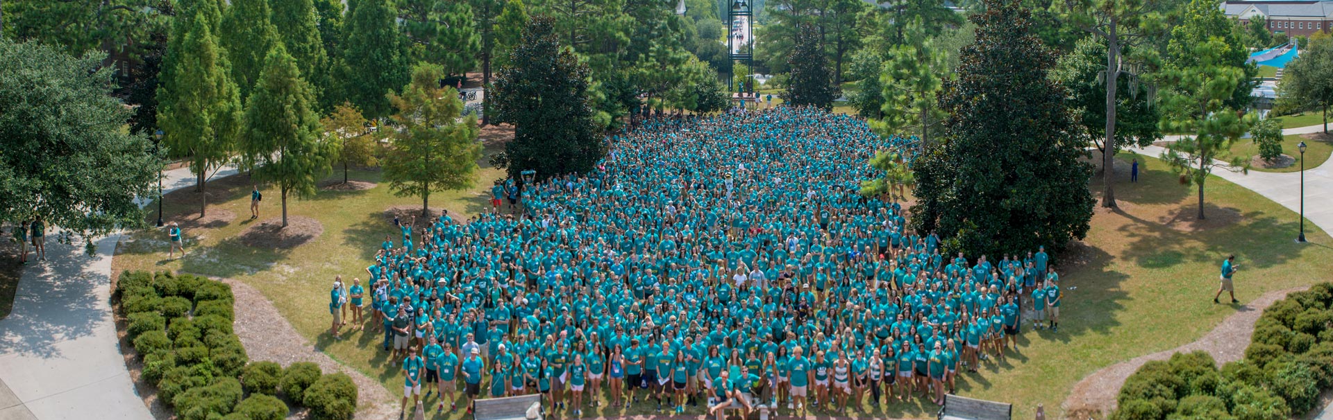First-Year Students wearing teal take a photo on Convocation day in front of the UNCW clocktower