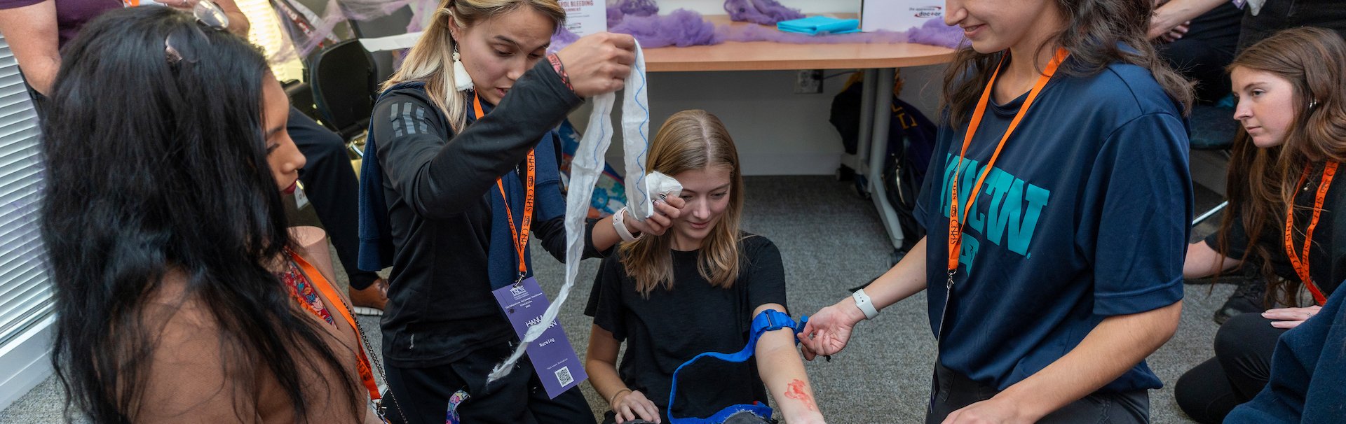 Several girls simulating a bleeding arm and treatment