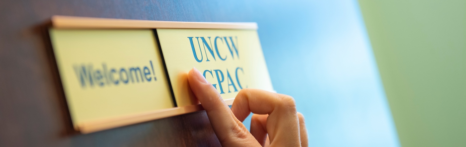 Hand pointing to Door with a GPAC name plate on it