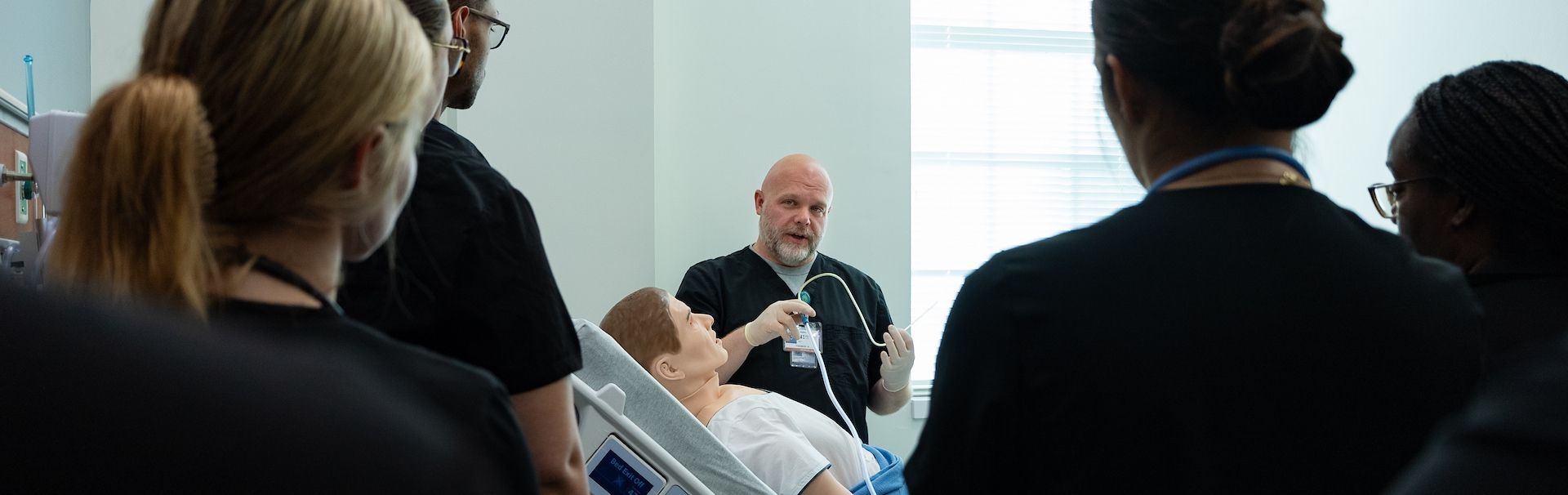 Student observe faculty make use of a Manikin to practice their skills in a lab simulation