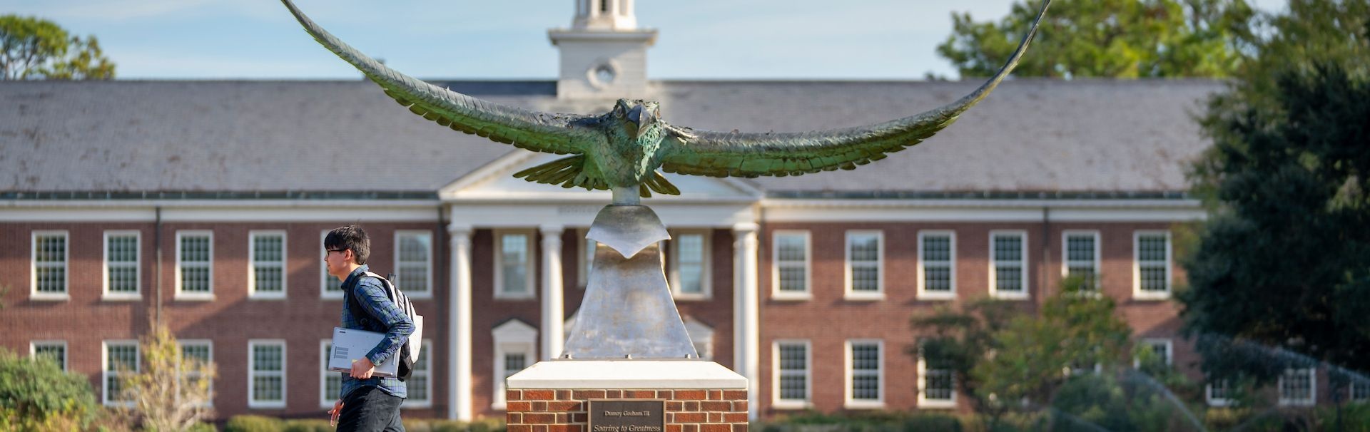 Student walking in front of a seahawk statue
