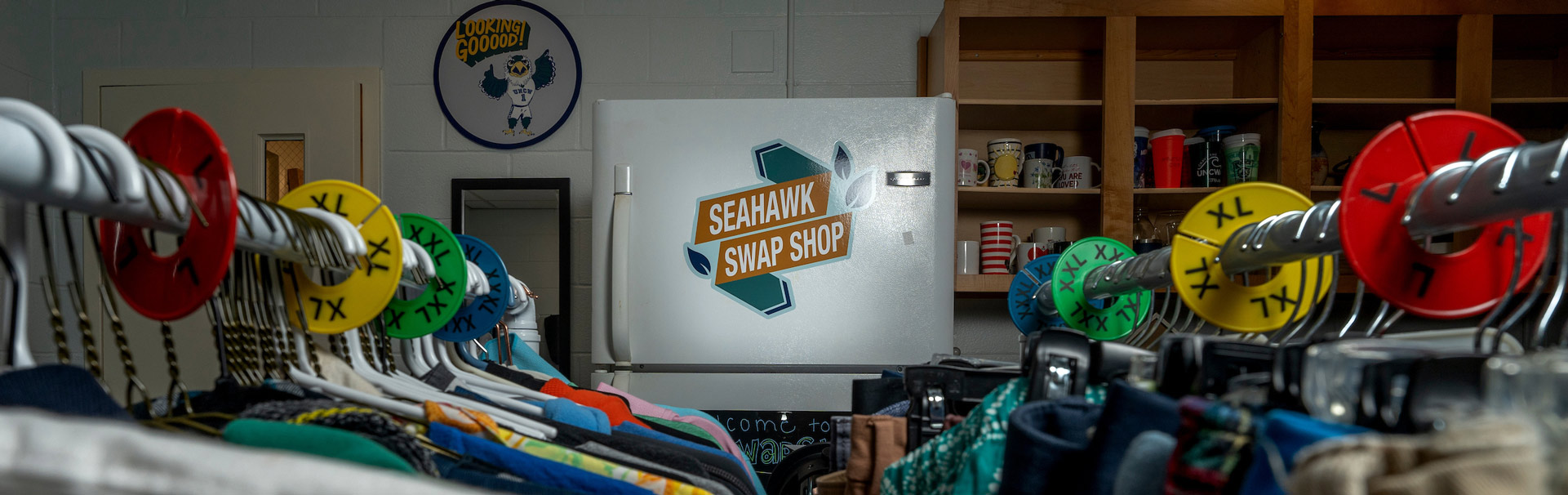Room with clothes hanging and a sign that says Seahawk swap shop