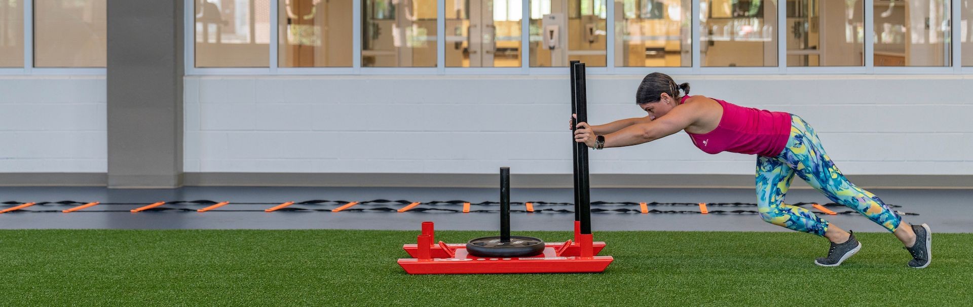 Woman doing sled push over turf