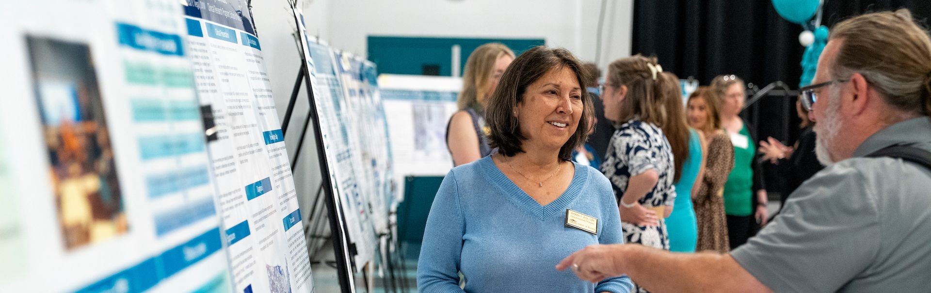 A woman presents her research poster presentation to a man