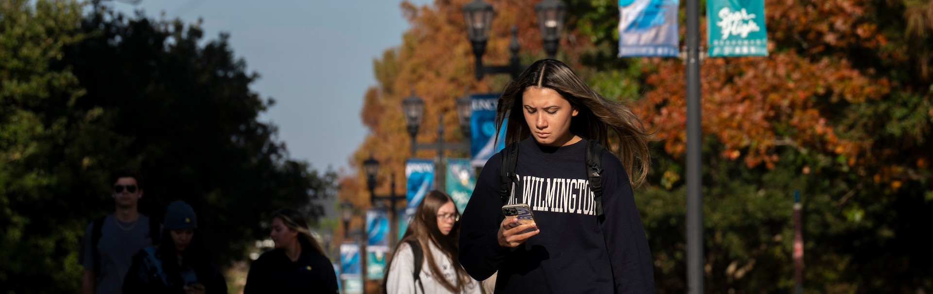 Student walking on campus while looking at their phone