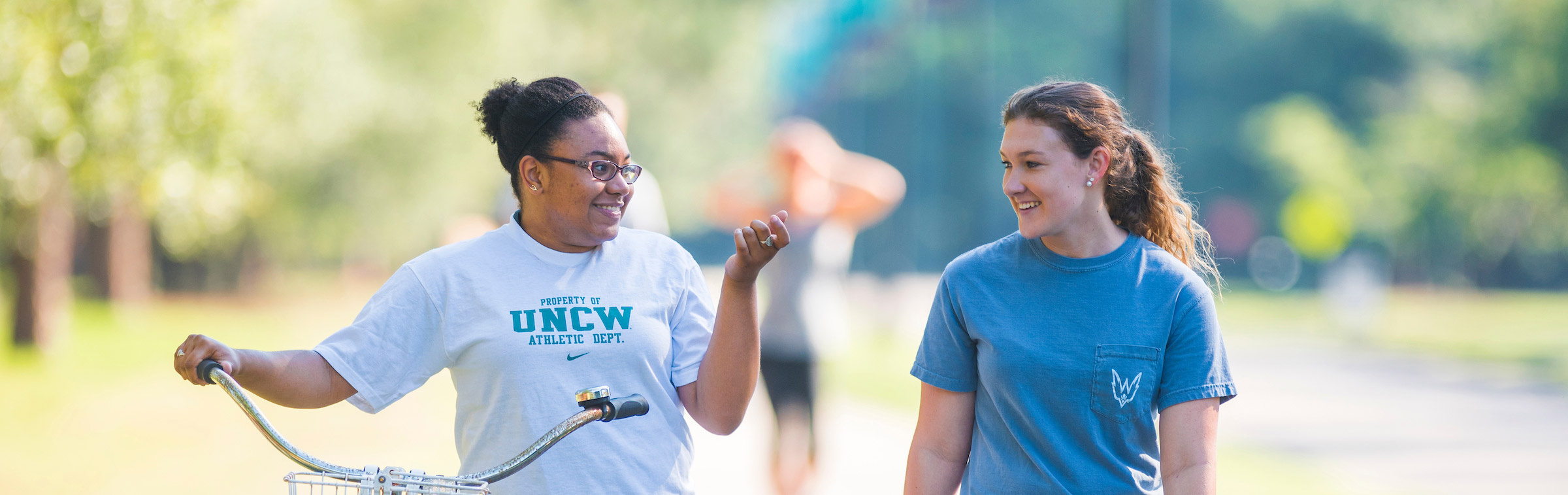 Two students are talking while they walk around campus during summer.