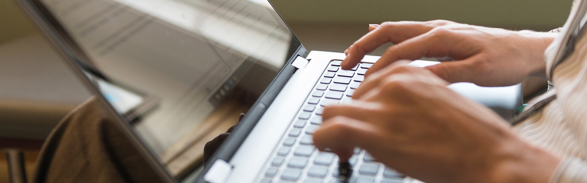 A close-up of a person's hands typing on a laptop and accessing the resources available on the myUNCW site for Academic Affairs.